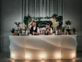 Dwóch barmanów przygotowuje drinki przy nowoczesnym, podświetlanym barze. To idealny drink bar na wesele, oferujący orzeźwiające napoje.