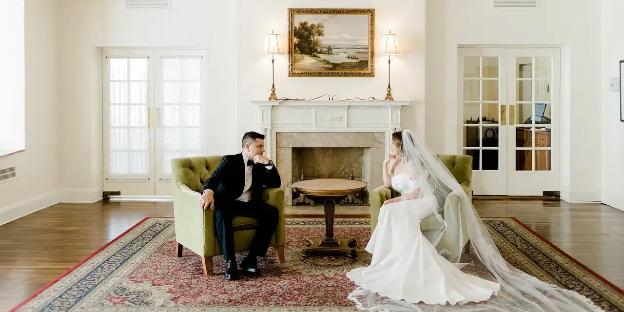 Para młoda siedzi naprzeciwko siebie w eleganckich fotelach. Zastanawiają się, ile trwa ślub cywilny, zanim rozpoczną swoją wspólną podróż.