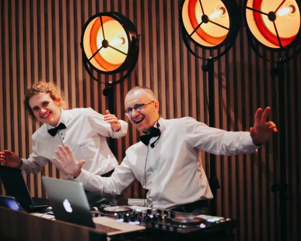 Dwóch DJ-ów w białych koszulach i czarnych muszkach, gotowych do zabawy. Zastanawiasz się, ile kosztuje dj na wesele?