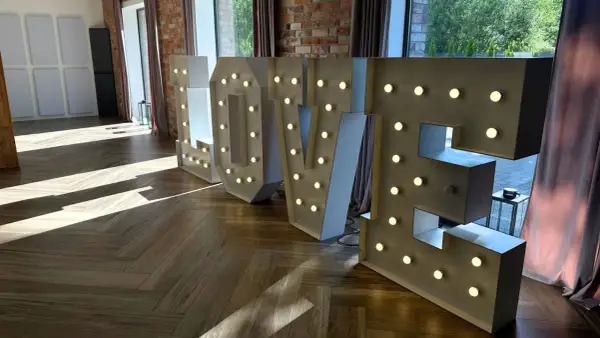 Podświetlane litery LOVE, idealne atrakcje na wesele, tworzą romantyczną atmosferę.